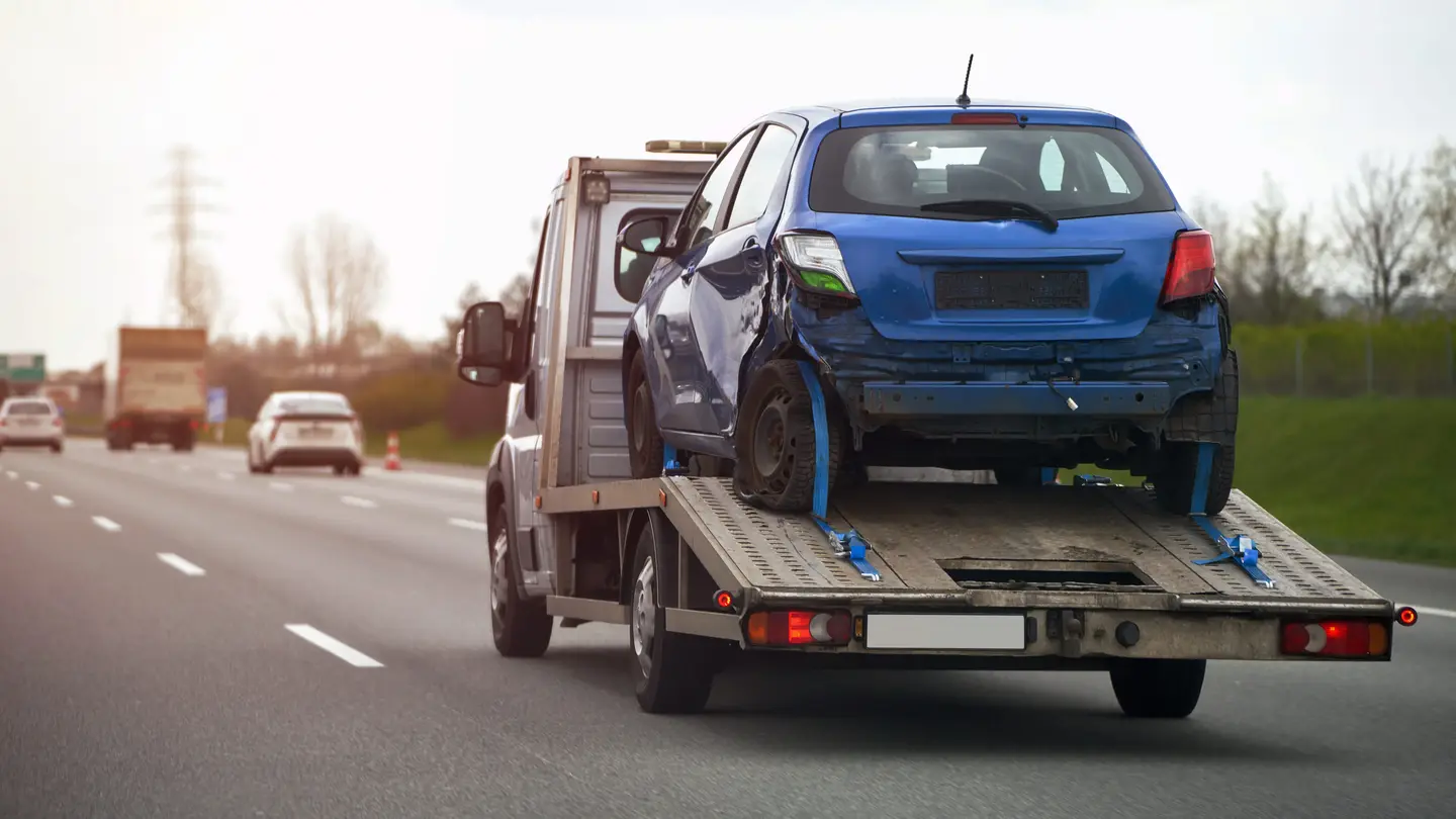 Blaues Abschleppwagen mit Unfallfahrzeug auf Autobahn